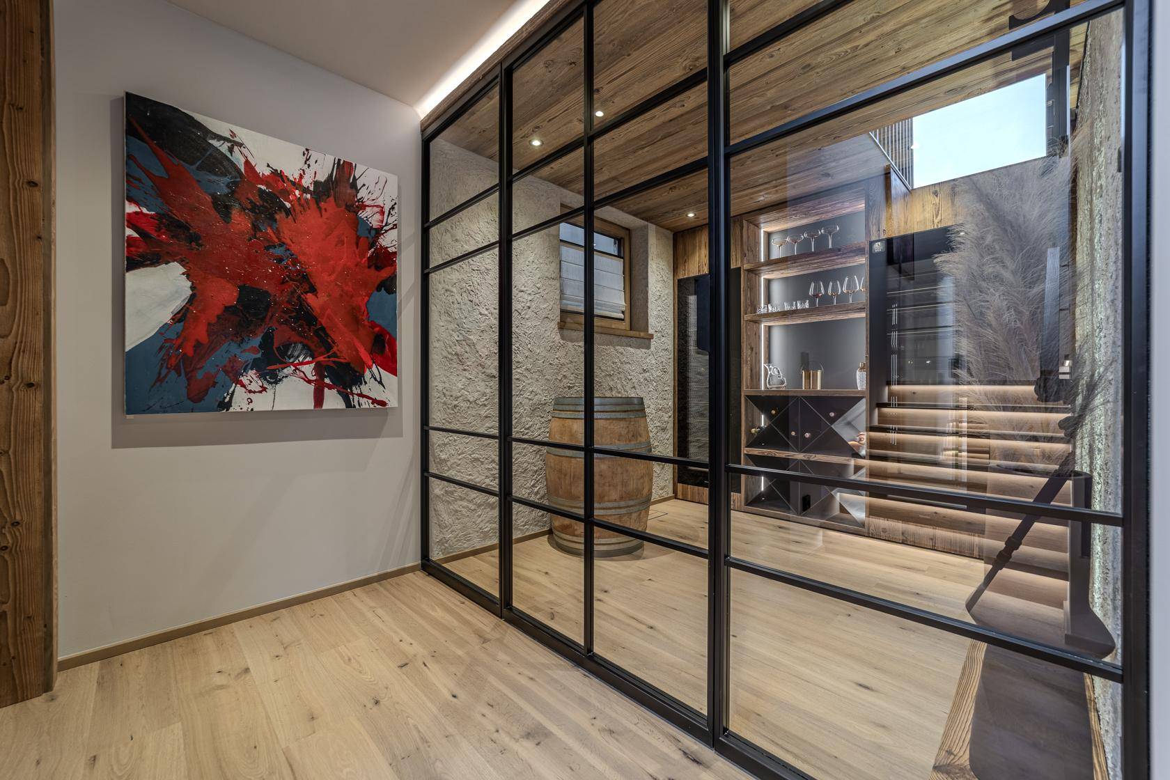Stilvoller Weinkeller mit Glasfront, Holzregalen und rustikalem Weinfass.