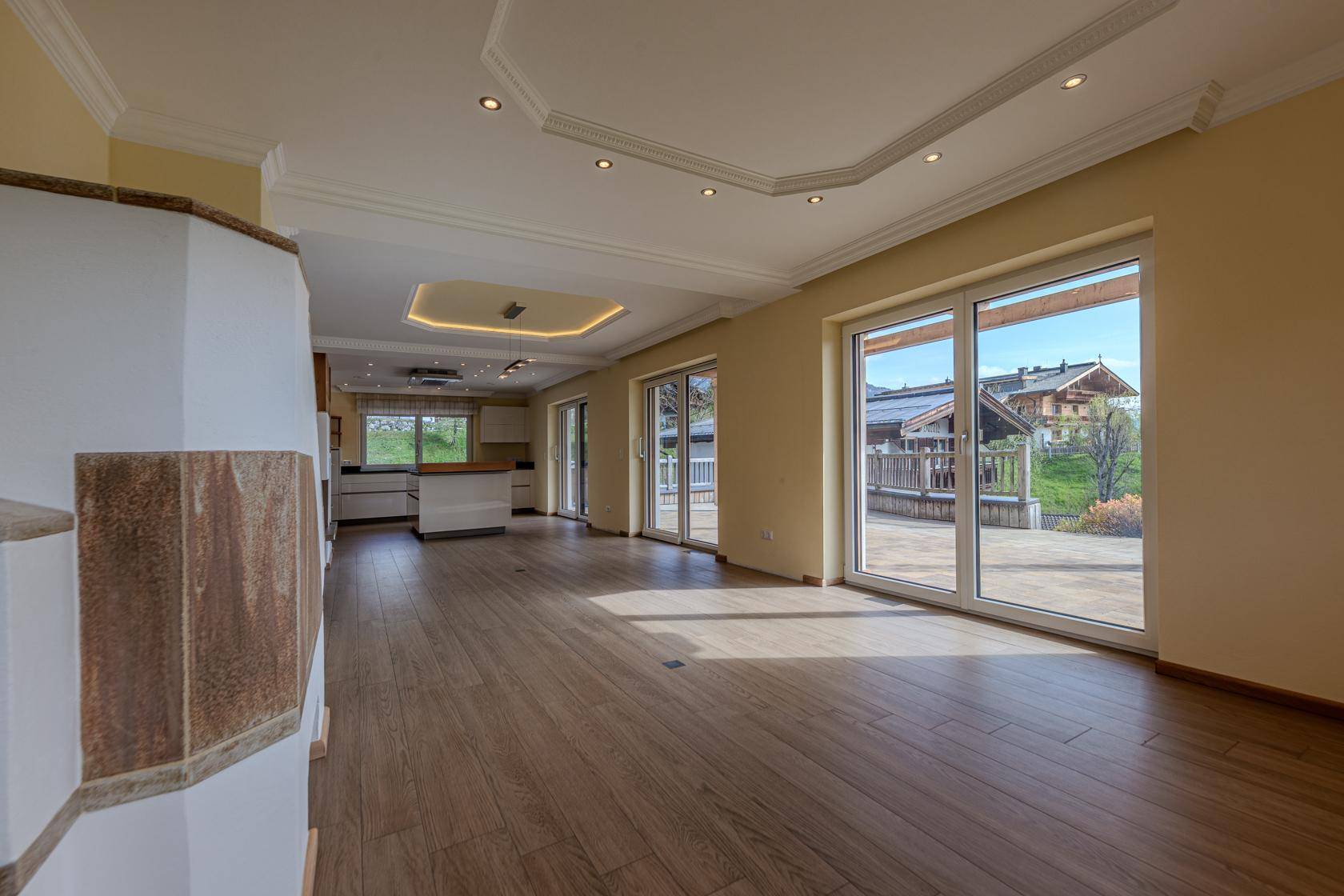 Heller offener Wohnbereich mit Holzboden, moderner Küche und Zugang zur Terrasse mit Bergblick.
