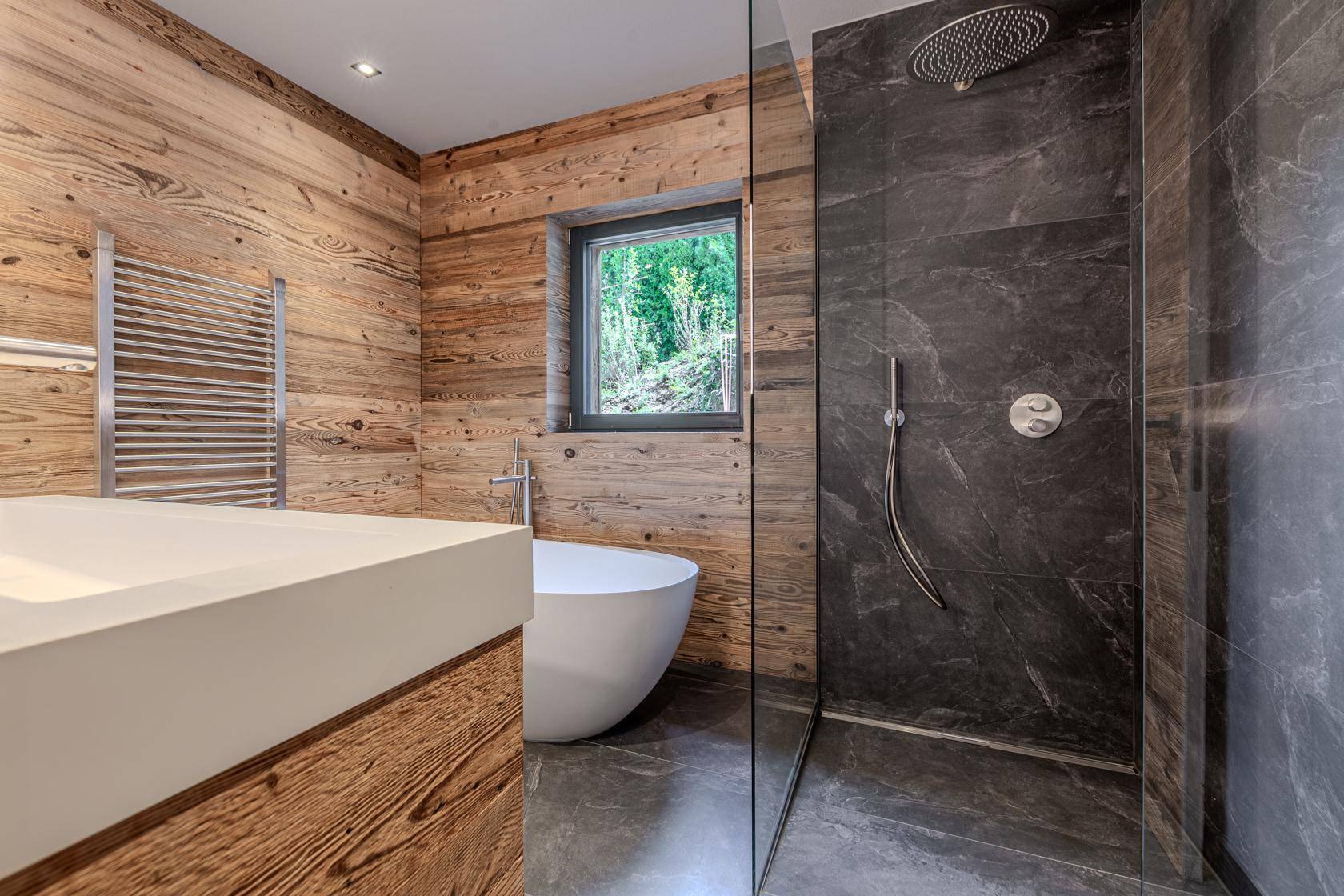 Modernes Badezimmer mit freistehender Badewanne, begehbarer Dusche und Holzverkleidung.