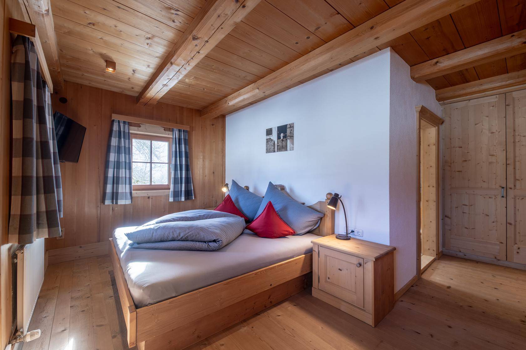 Gemütliches Schlafzimmer mit Holzboden, Holzbalkendecke und traditionellem Doppelbett.
