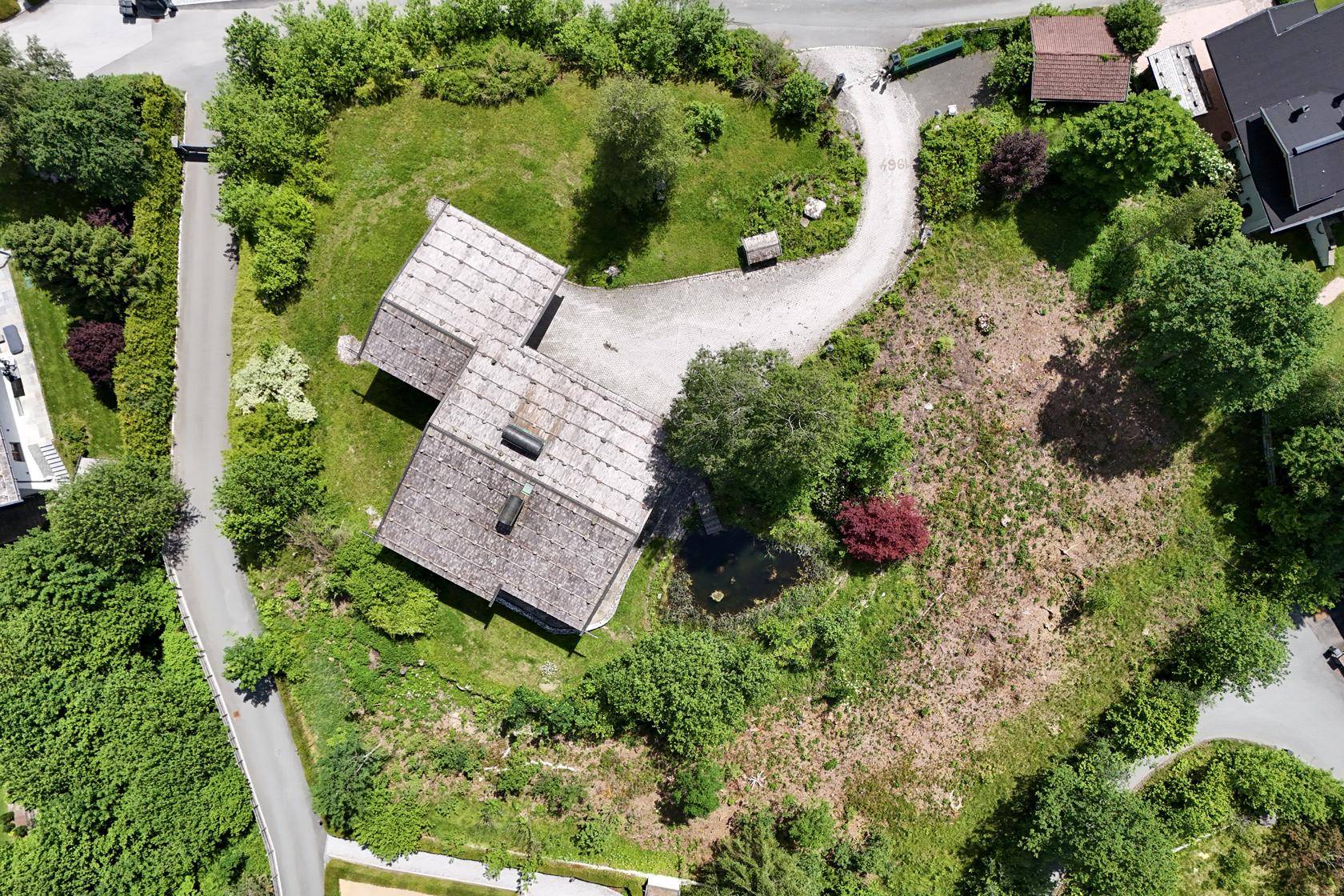 Luftaufnahme des Anwesens mit Haus, Zufahrt und weitläufigem grünen Grundstück.