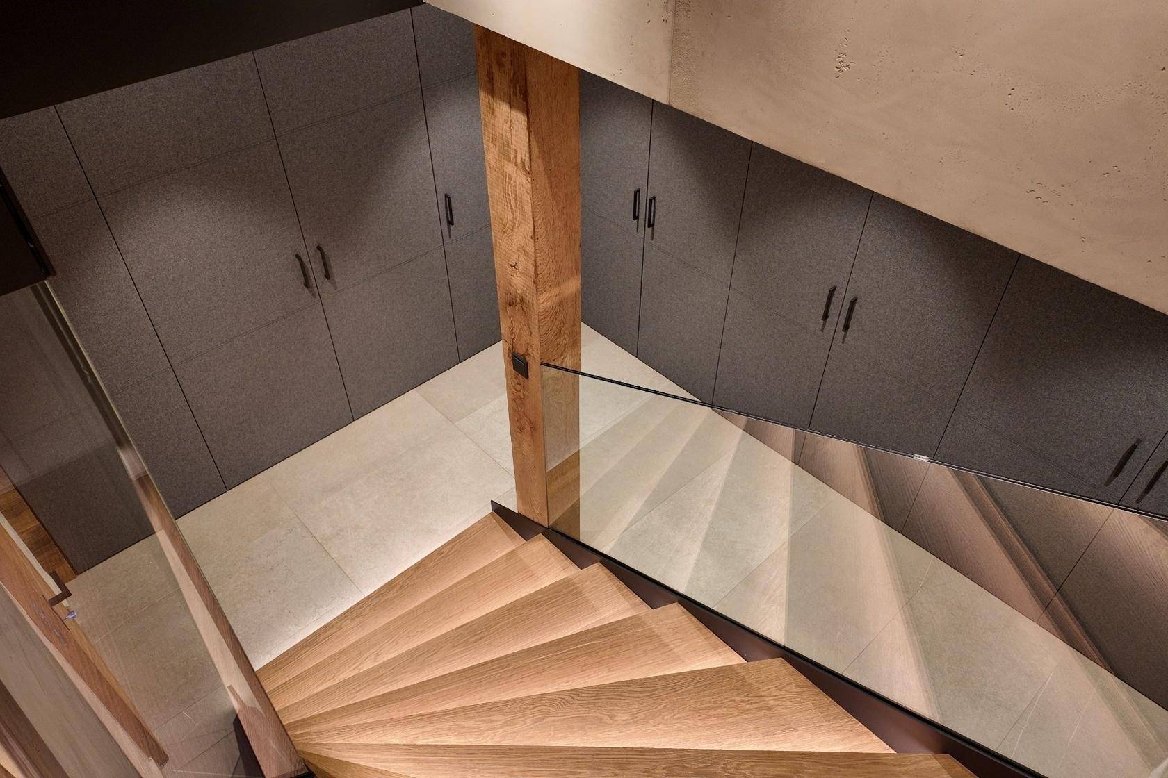 Elegante Holztreppe mit Glasgeländer und integrierten Schränken im Flurbereich.
