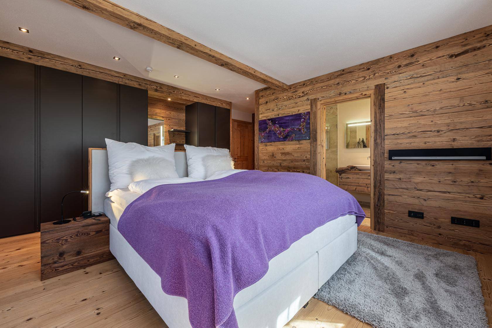 Modernes Schlafzimmer mit Holzwänden, Einbauschränken und direktem Zugang zum Badezimmer.