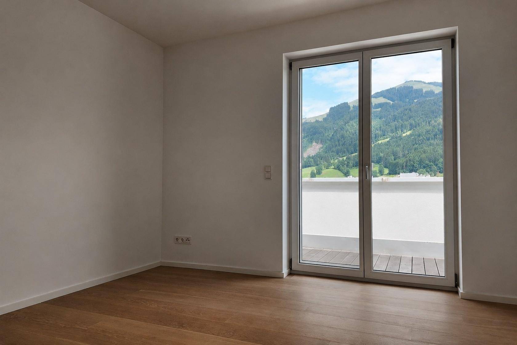 Helles Zimmer mit Holzboden und großem Fenster, das einen weiten Blick auf die Berge bietet.