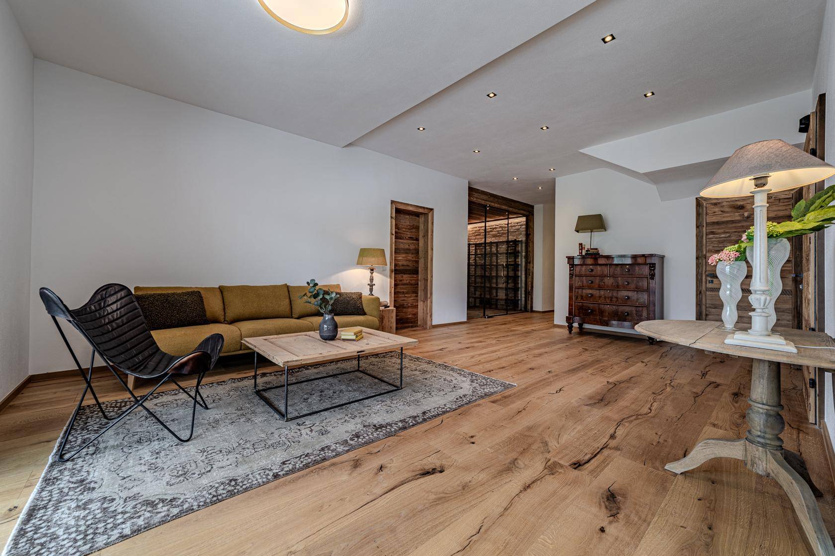 Gemütlicher Wohnbereich mit Holzboden, Sofa und traditionellen Holzmöbeln.