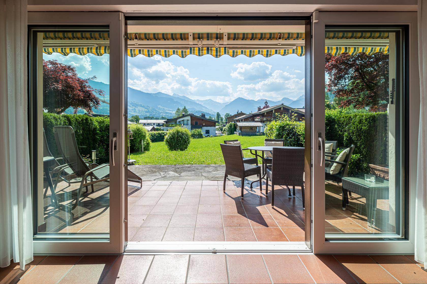 Großzügige Terrasse mit Gartenmöbeln und weitem Blick auf die umliegende Berglandschaft.