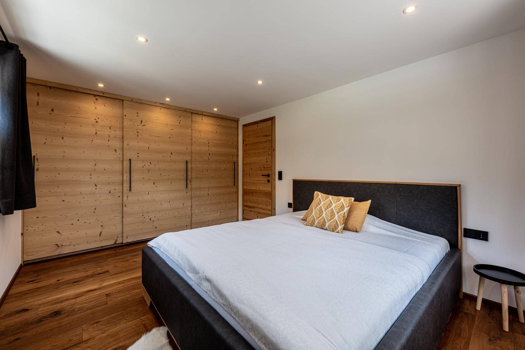 Helles Schlafzimmer mit Holzboden, Einbauschränken und modernem Doppelbett.