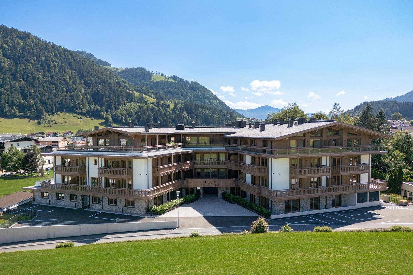 Neubau im alpinen Stil mit mehreren Balkonen und Blick auf die umliegende Bergwelt.
