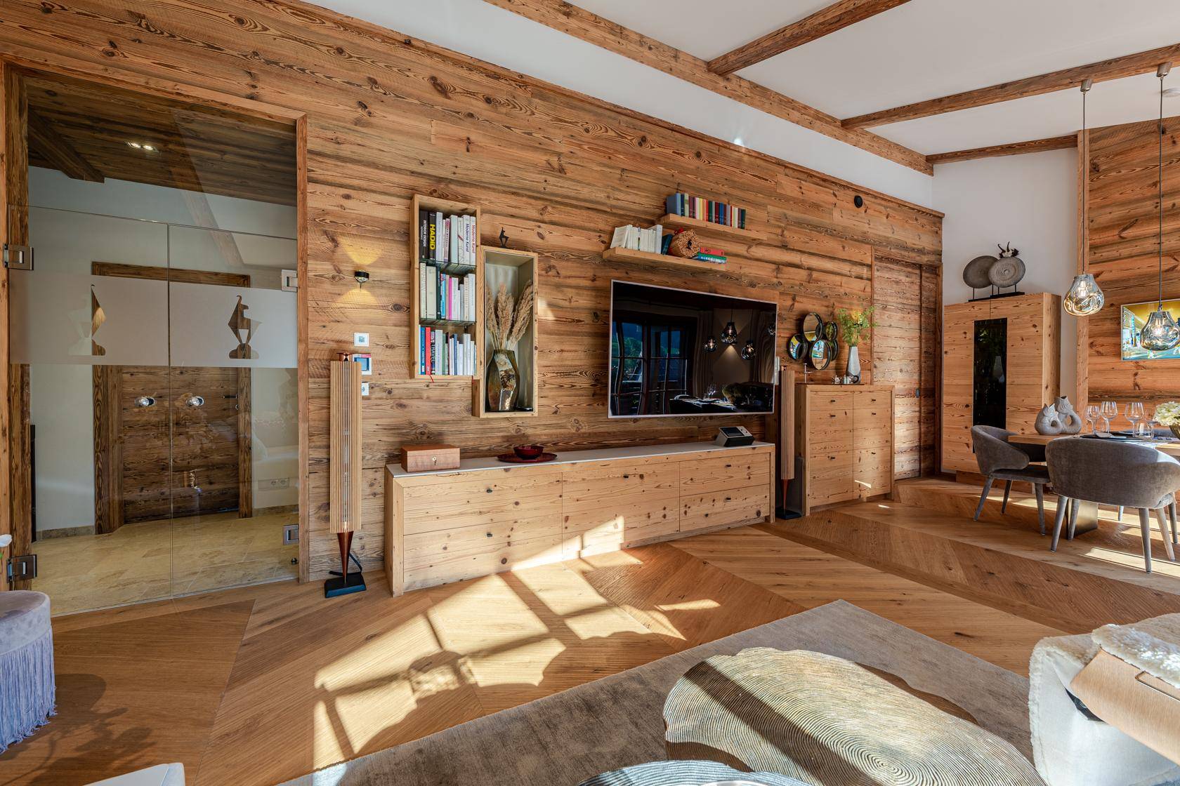 Geräumiges Wohnzimmer mit Holzwänden, Fernseher und Blick auf den Essbereich.