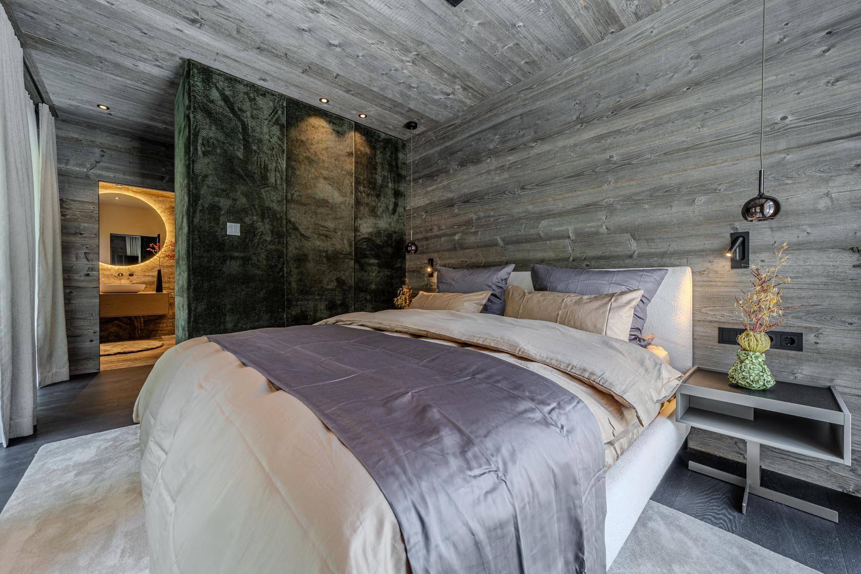 Modernes Schlafzimmer mit Holzwänden und -decke, großem Bett und offenem Zugang zum Badezimmer.