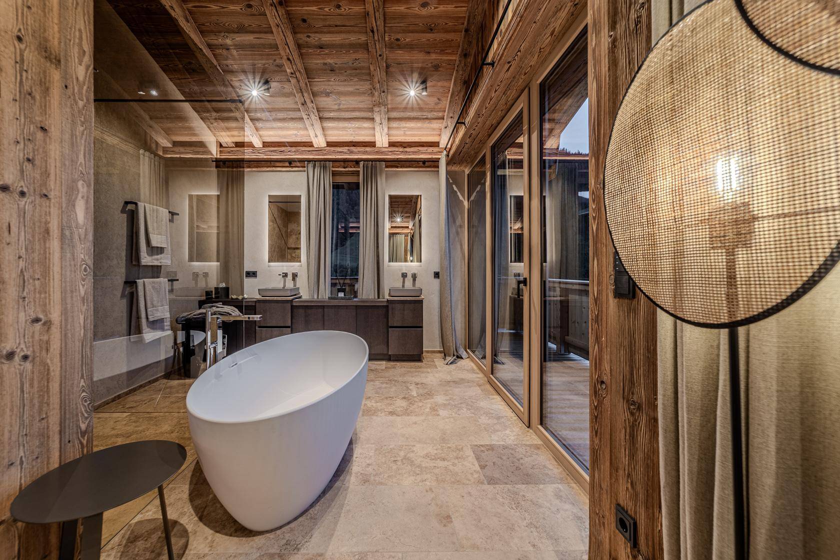 Modernes Badezimmer mit freistehender Badewanne, Doppelwaschbecken und Natursteinboden.