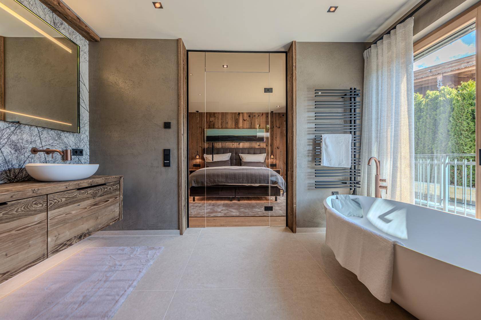 Modernes Badezimmer mit freistehender Badewanne, Einzelwaschbecken und Zugang zum Schlafzimmer.