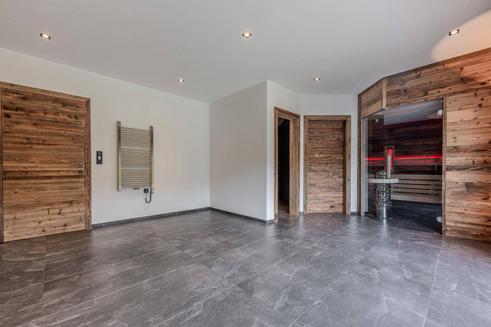 Geräumiger Raum mit Fliesenboden und Sauna, ideal als zukünftiger Wellnessbereich.