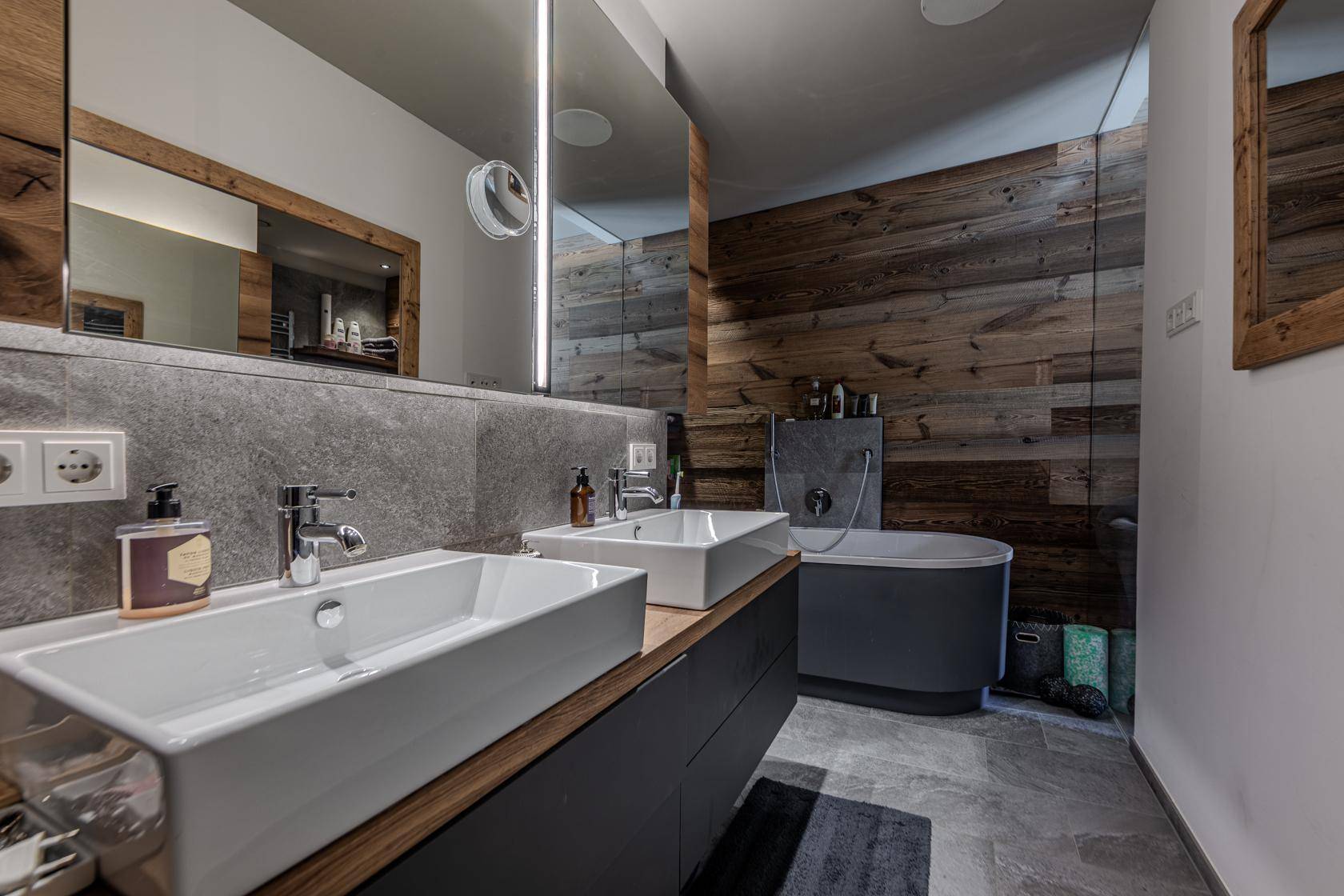 Modernes Badezimmer mit Doppelwaschbecken, freistehender Badewanne und Holzakzenten.