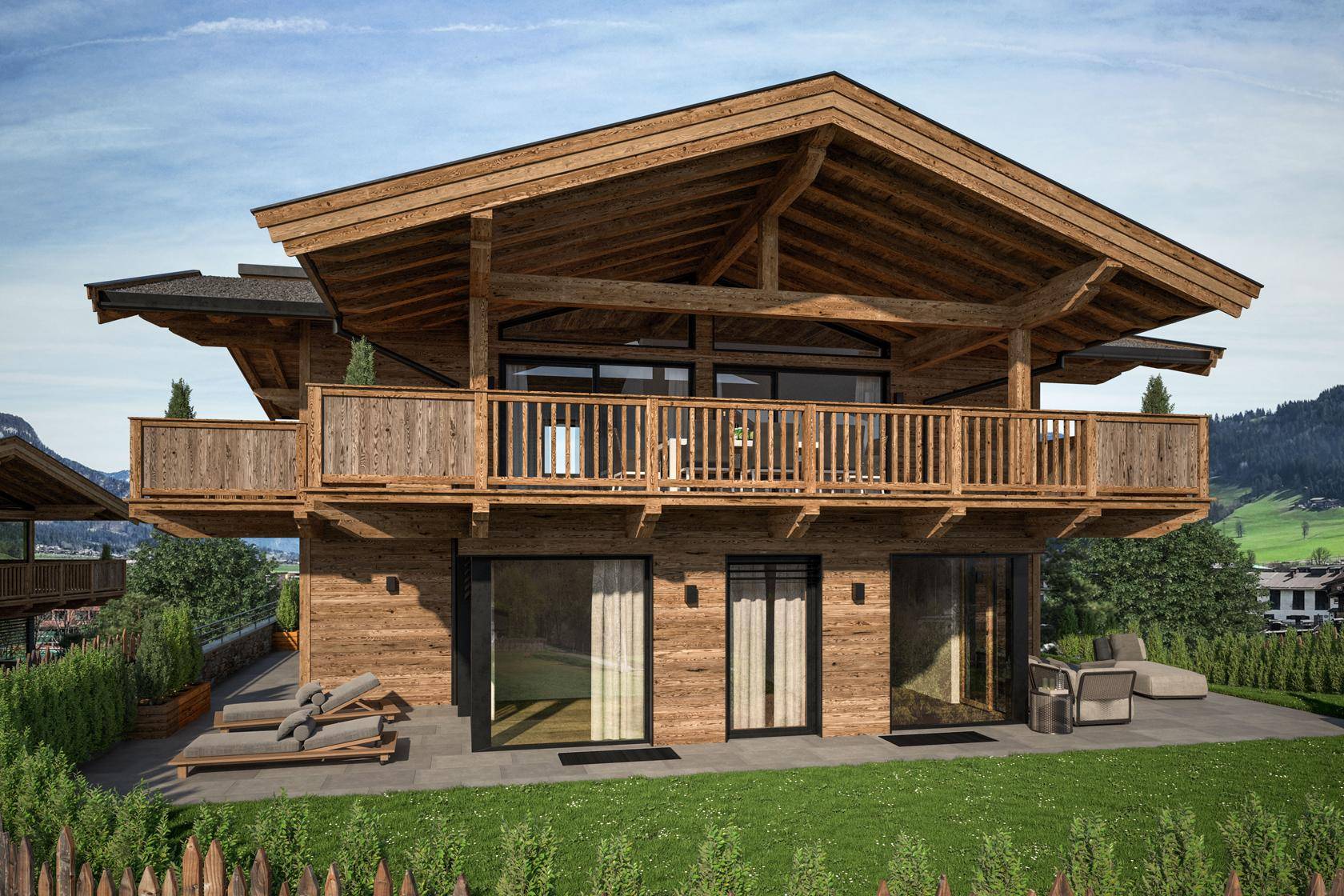 Rückseite des Chalets mit großer Terrasse, Liegestühlen und Blick ins Grüne.