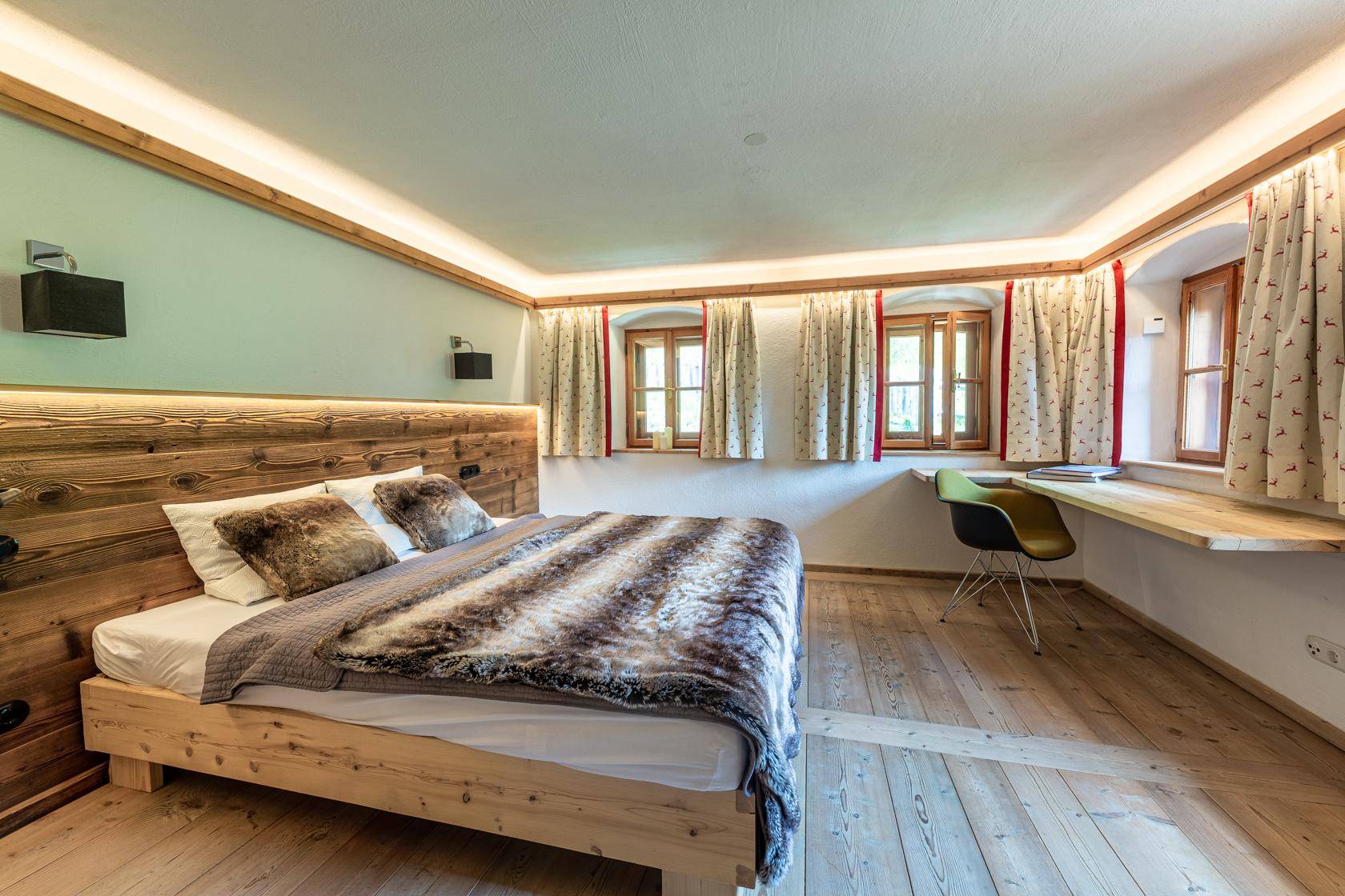 Gemütliches Schlafzimmer mit Holzboden, indirekter Beleuchtung und traditionellen Fenstern.