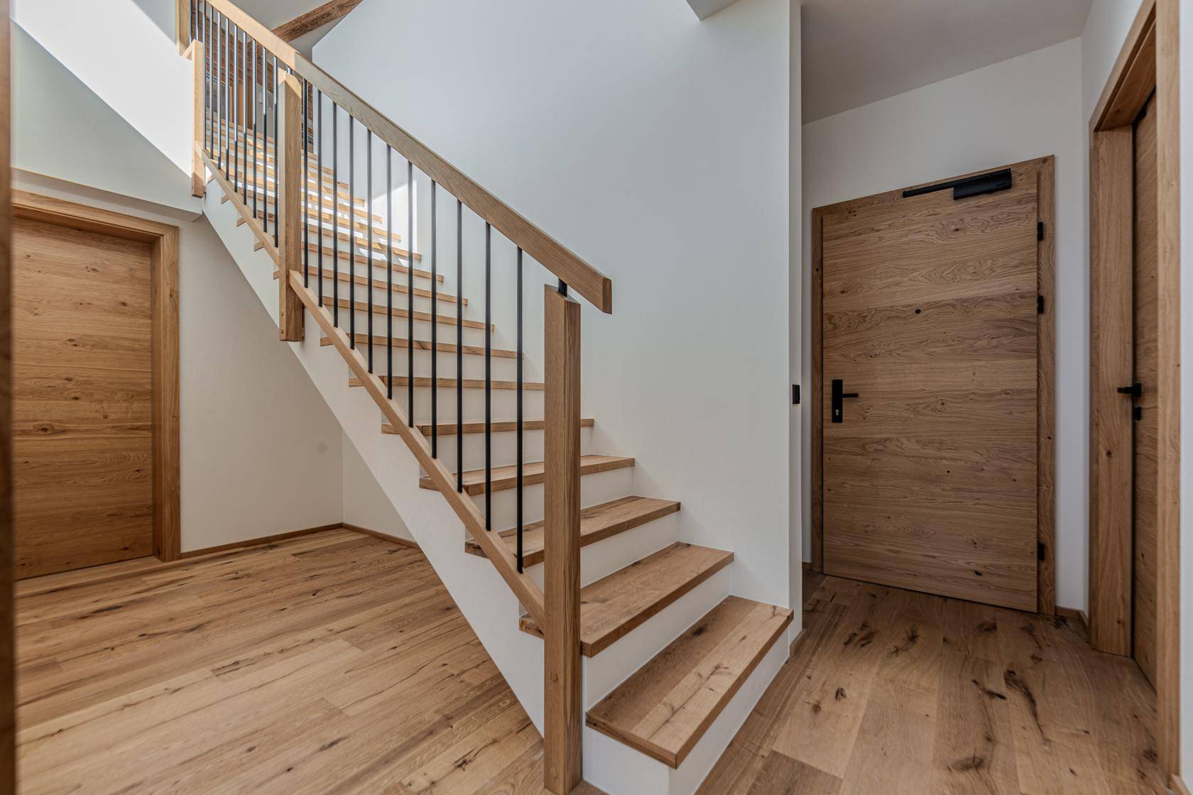 Heller Flur mit Holztreppe, Holzboden und passenden Holztüren.