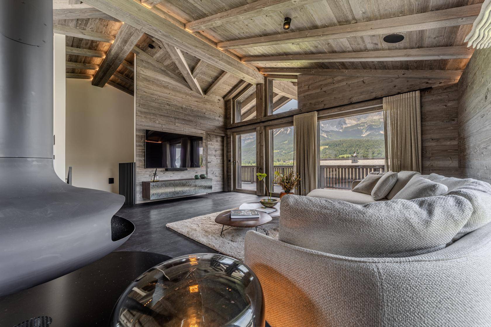 Gemütlicher Wohnbereich mit bequemer Sitzecke, Fernseher und Hängekamin, mit Bergblick.