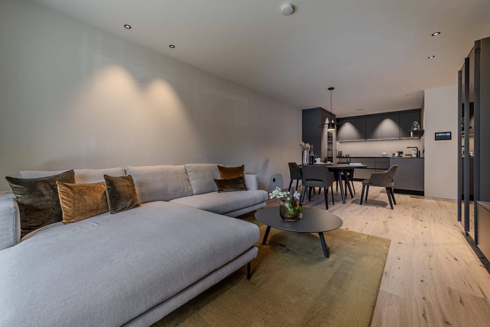 Geräumiger offener Wohn- und Essbereich mit bequemer Couch, Holzboden und moderner Einrichtung.