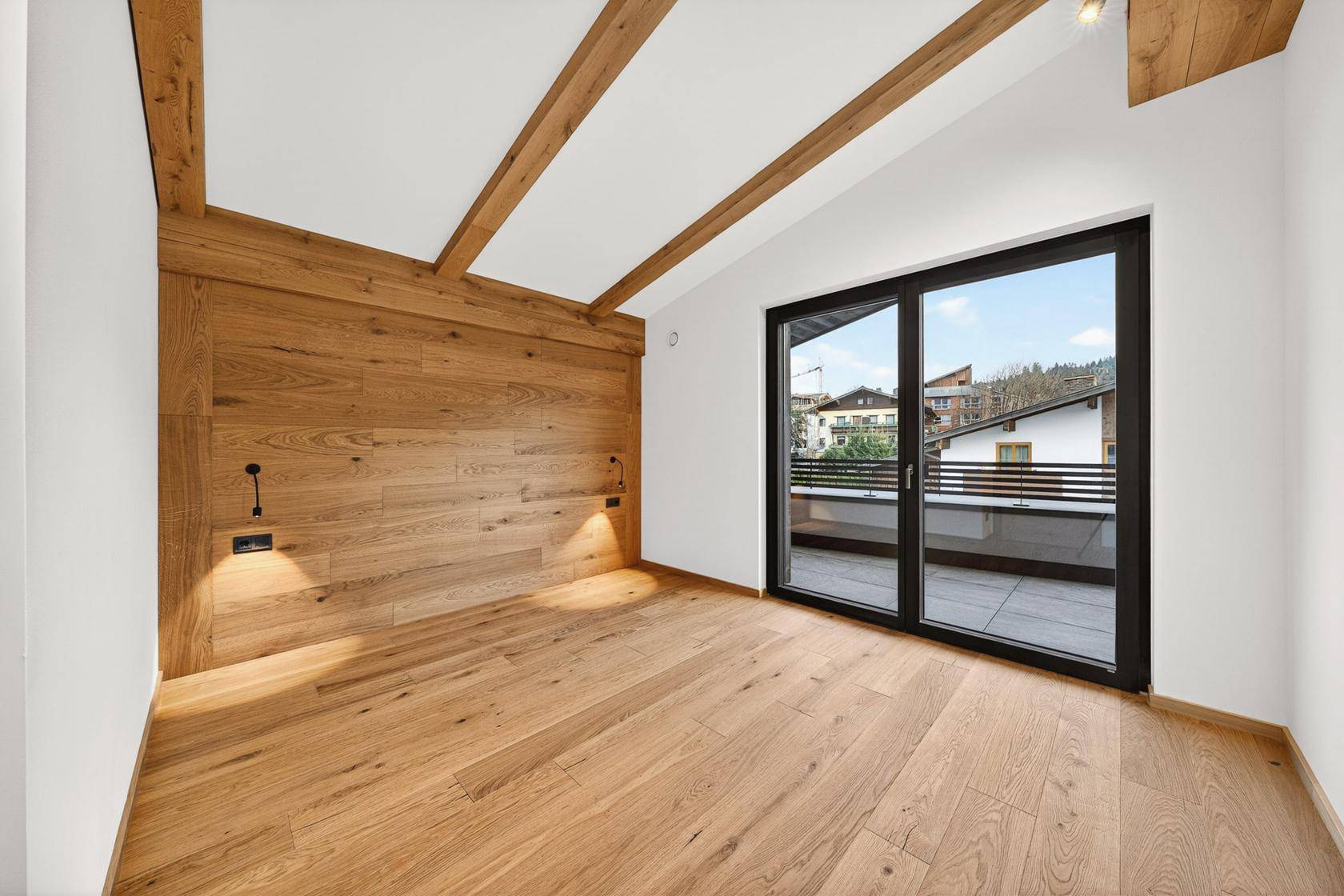 Helles Schlafzimmer mit Holzwand, Holzbalkendecke und Zugang zu einer privaten Terrasse mit Bergblick.