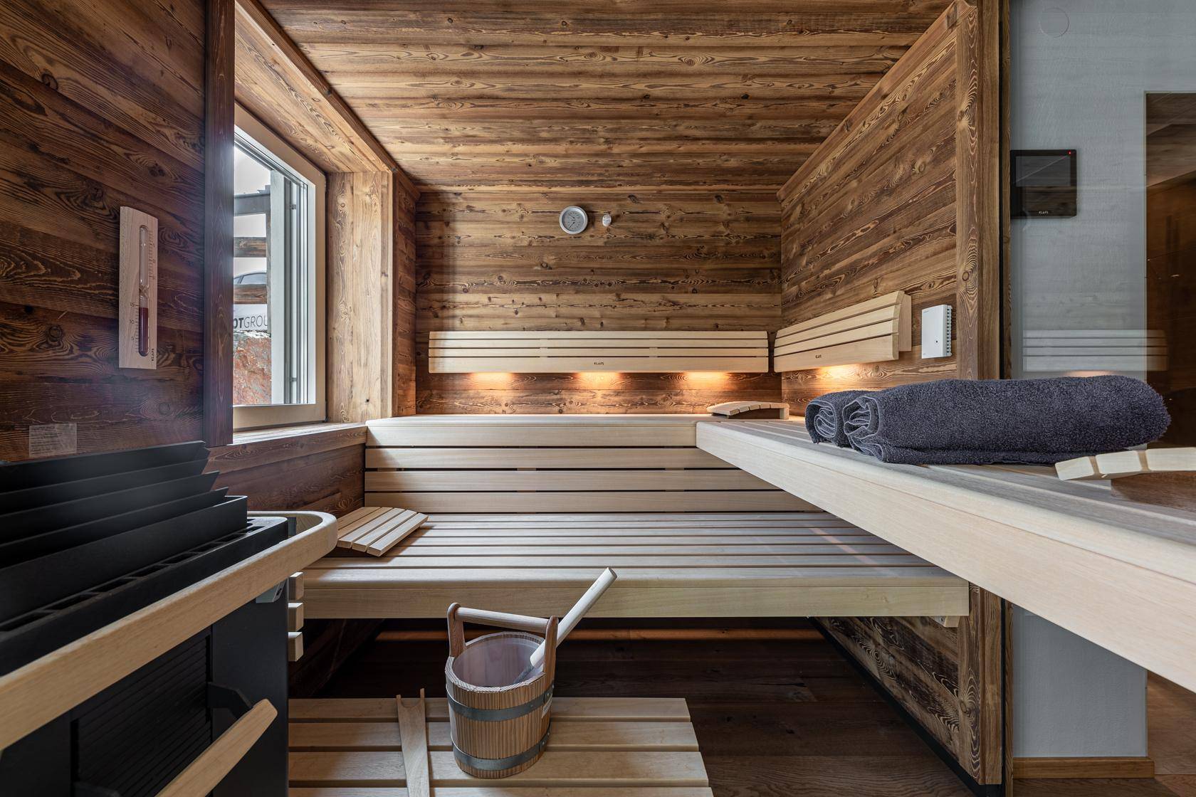 Traditionelle Holzsauna mit Bänken und Saunaofen für entspannende Momente.