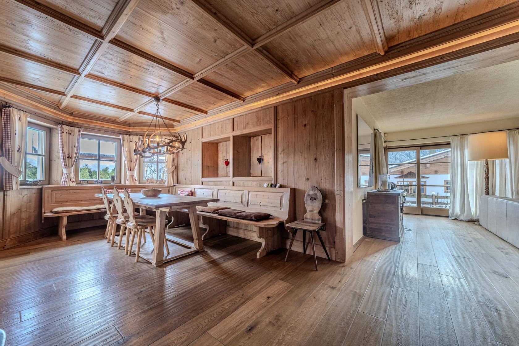 Geräumiger Essbereich im Chalet-Stil mit Holzelementen und Zugang zu einem hellen Wohnbereich.