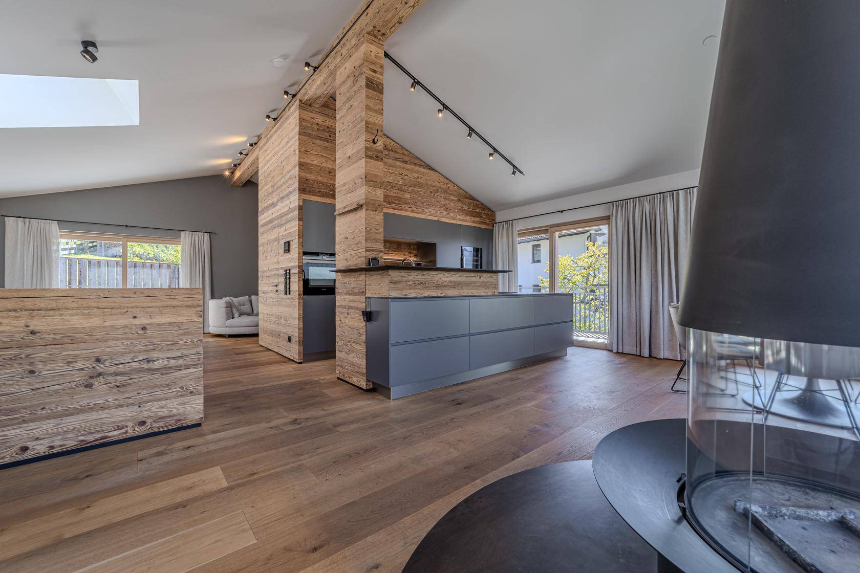 Offene Küche mit grauen Fronten und Holzelementen, verbunden mit dem Essbereich.