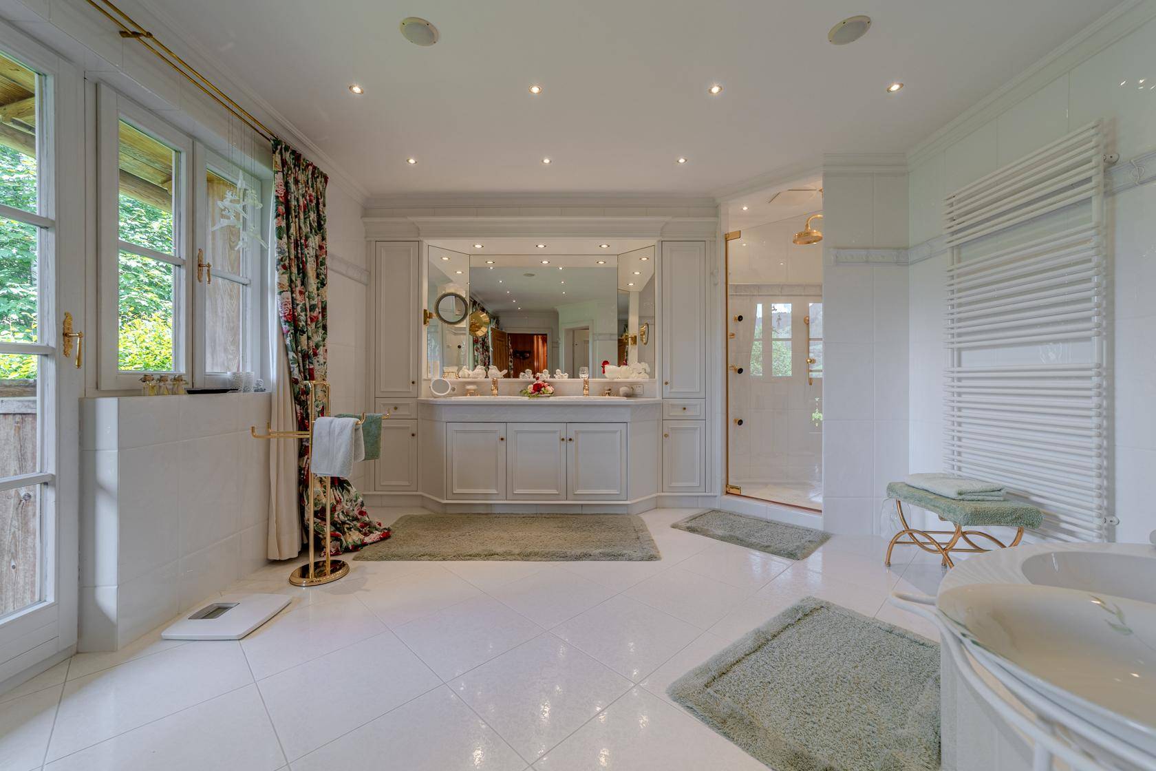 Luxuriöses Badezimmer mit Doppelwaschbecken, großer Dusche, Badewanne und Zugang zum Balkon.