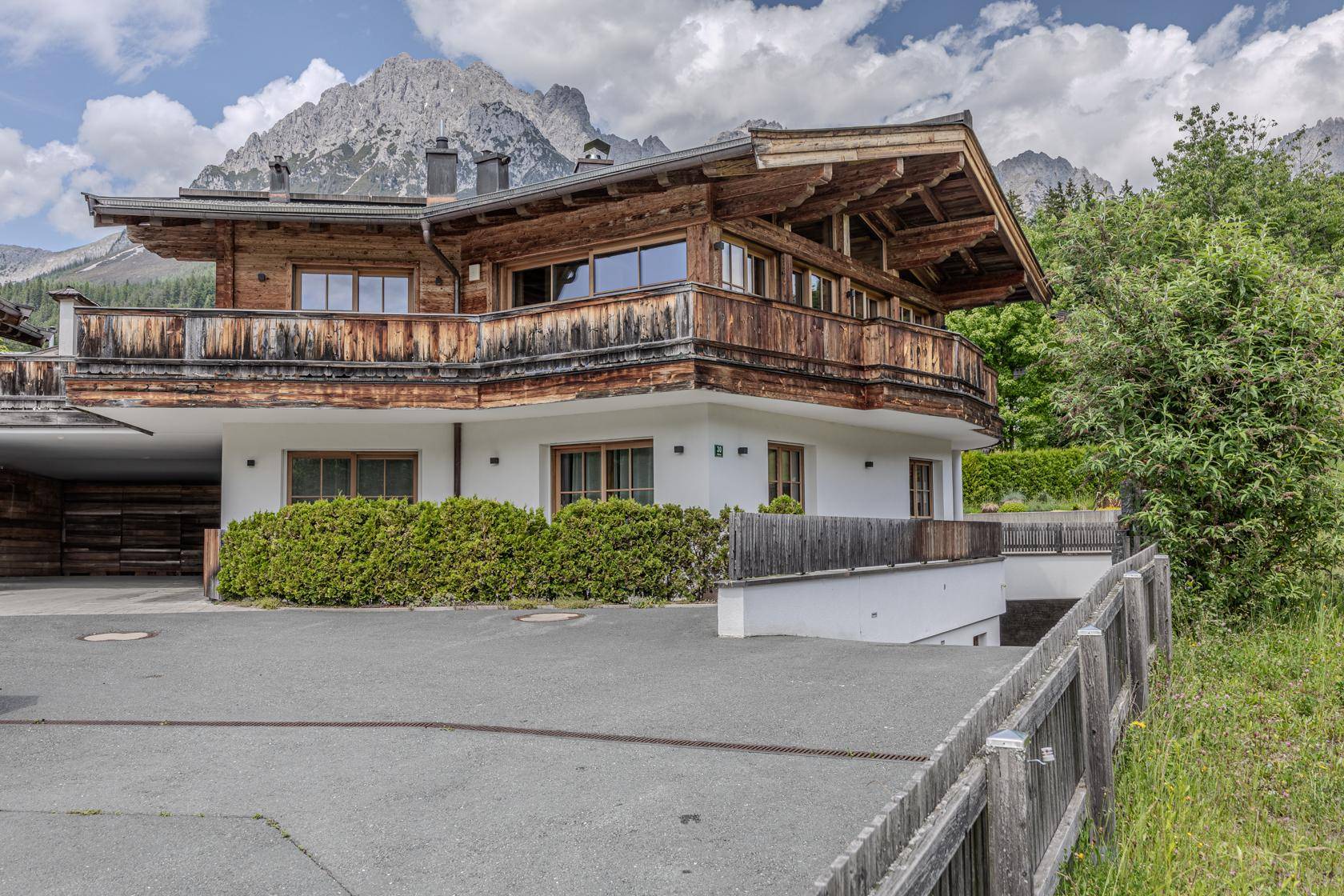 Traditionelles Holzhaus im alpinen Stil mit Bergblick und Zufahrt zur Tiefgarage.