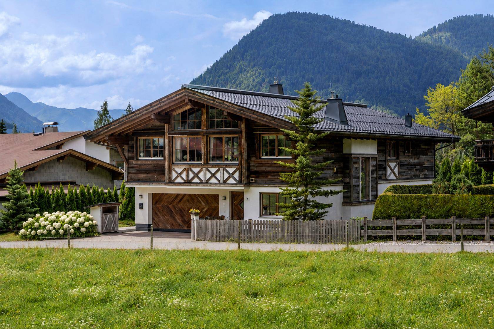 Idyllisches Chalet vor beeindruckender Bergkulisse mit weitläufiger Grünfläche und gepflegtem Garten.