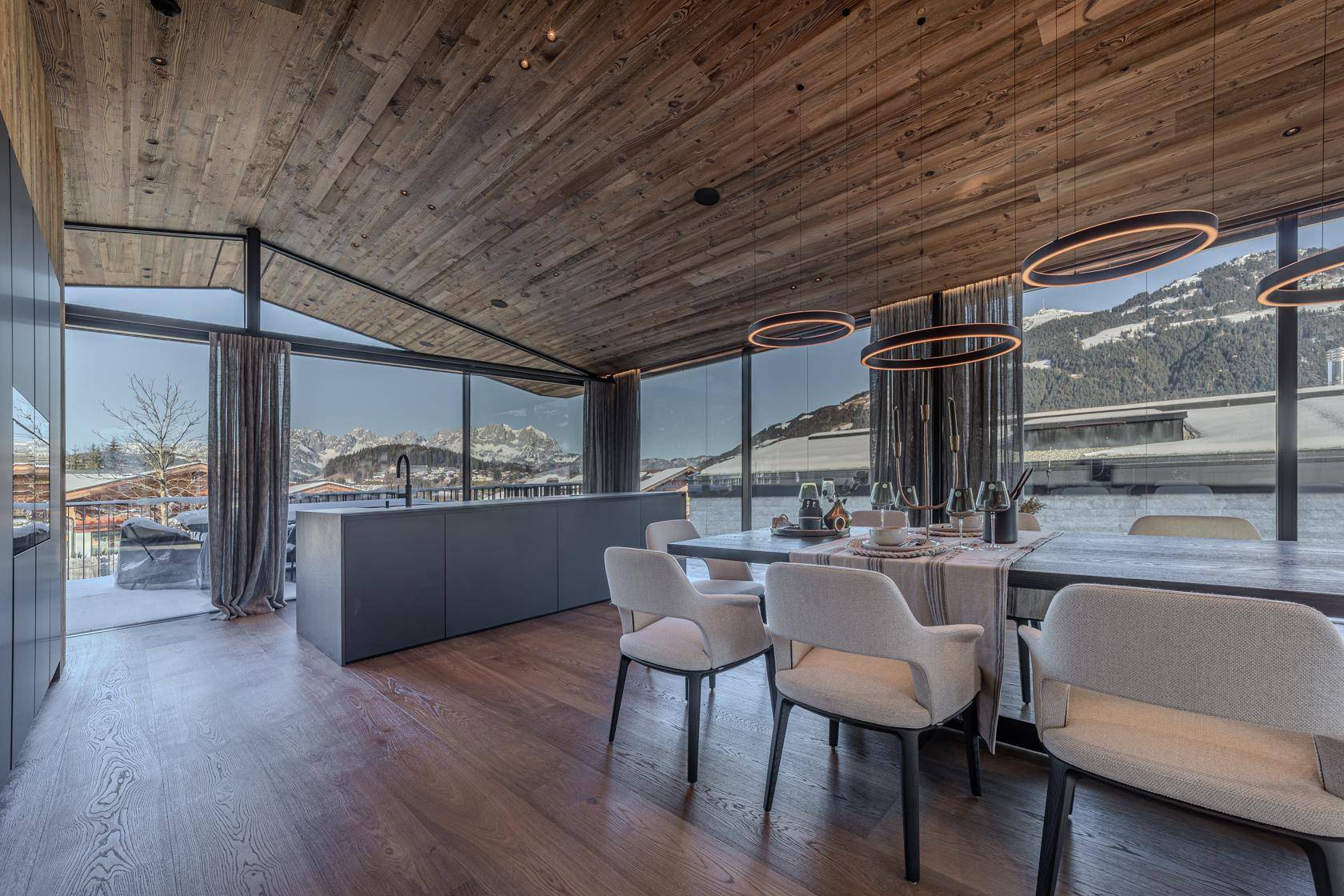 Moderner Essbereich mit Holzboden, Designerleuchten und raumhohen Fenstern mit Bergblick.