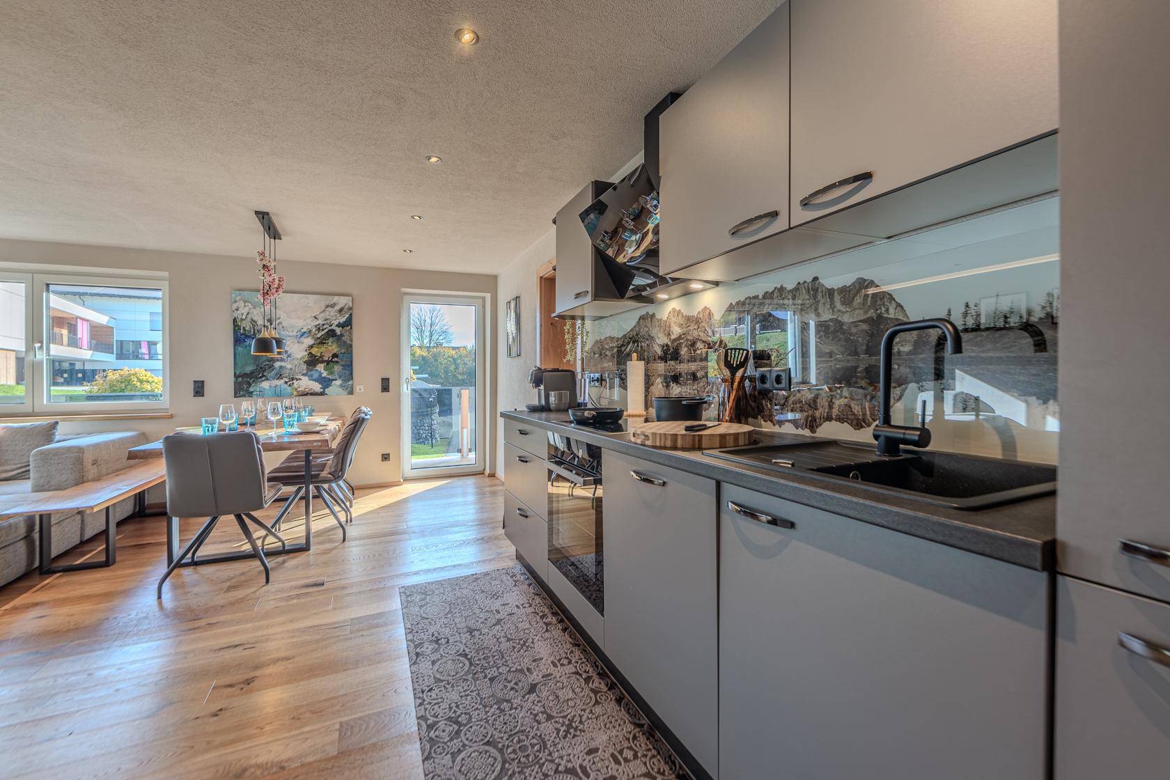 Moderne Einbauküche mit grauen Fronten, Holzboden und Blick in den Essbereich.