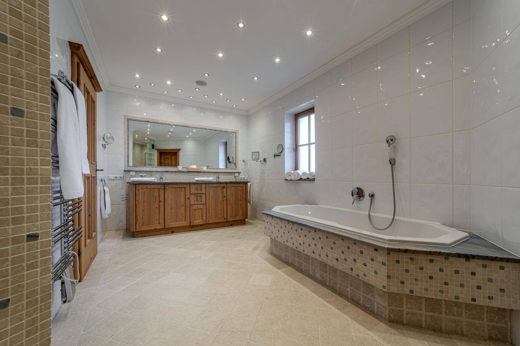 Geräumiges Badezimmer mit Eckbadewanne, Doppelwaschbecken und hellen Fliesen.