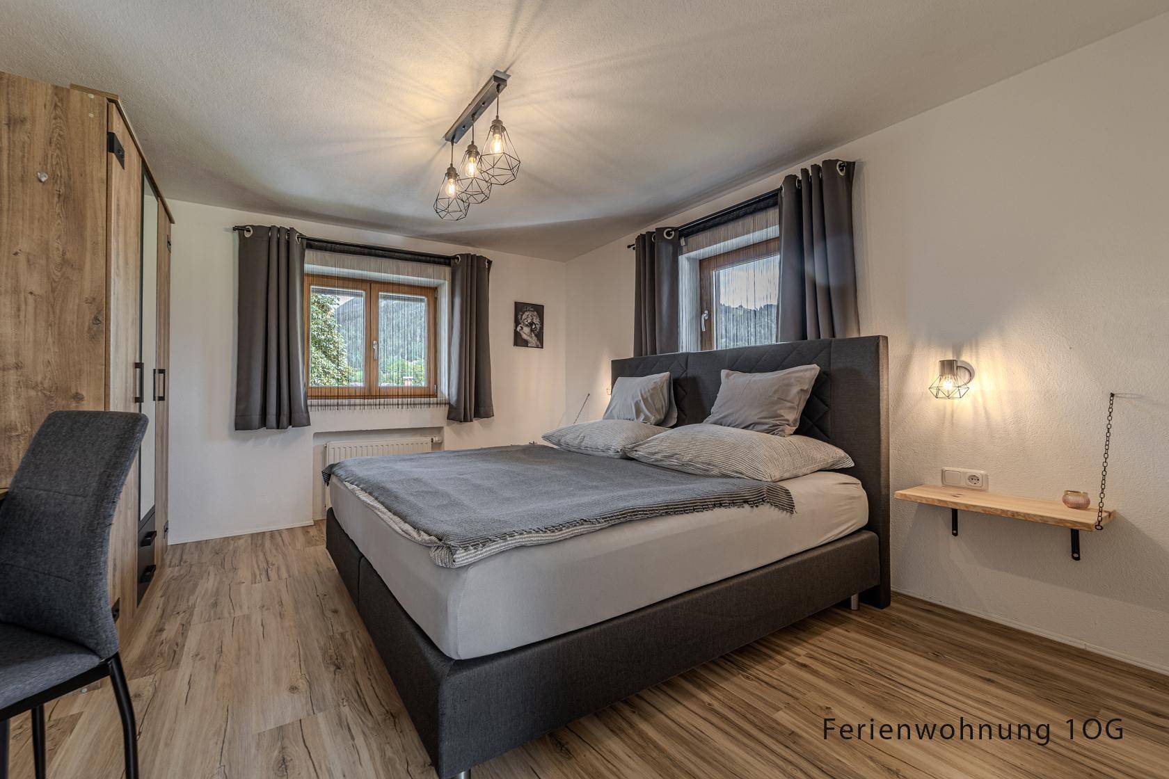 Schlafzimmer mit Doppelbett, Holzboden und Fenster mit Blick auf die Landschaft.