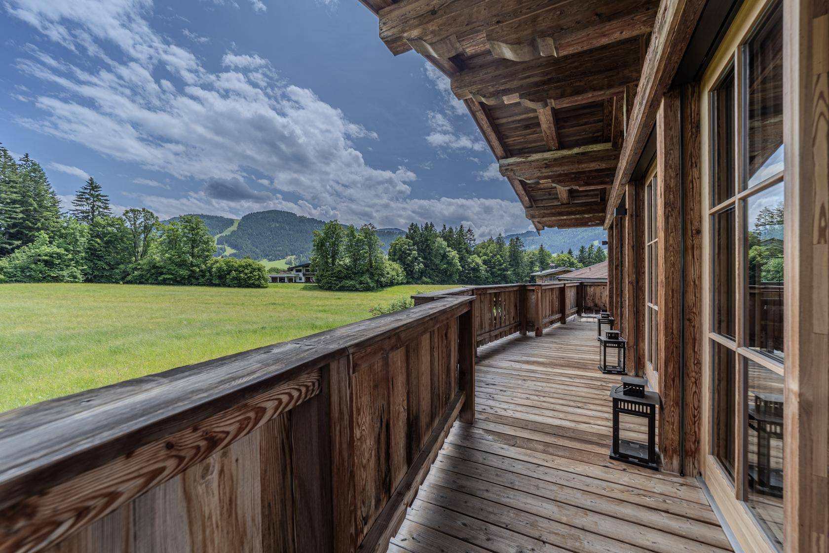 Langer Holzbalkon mit traditionellem Geländer und weitem Blick über die Landschaft.