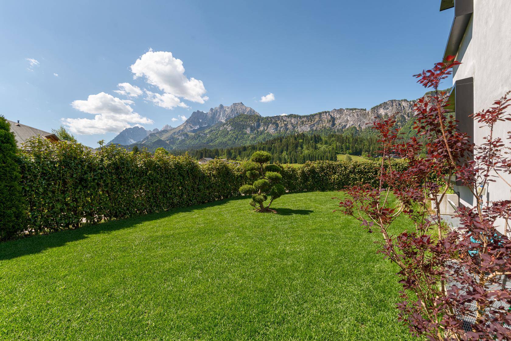 Großer, gepflegter Garten mit Rasenfläche und beeindruckendem Bergblick.
