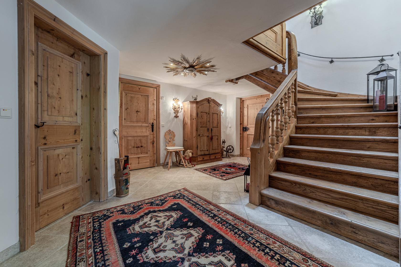 Geräumiger Flur mit Holztreppe, traditionellen Möbeln und Teppichen im Landhausstil.
