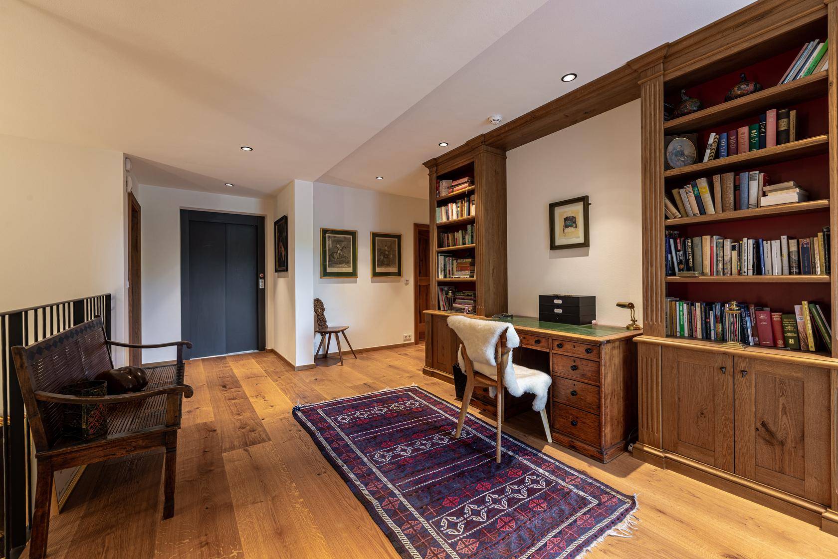 Heller Arbeitsbereich mit Holzboden, eingebauten Bücherregalen und traditionellem Schreibtisch.