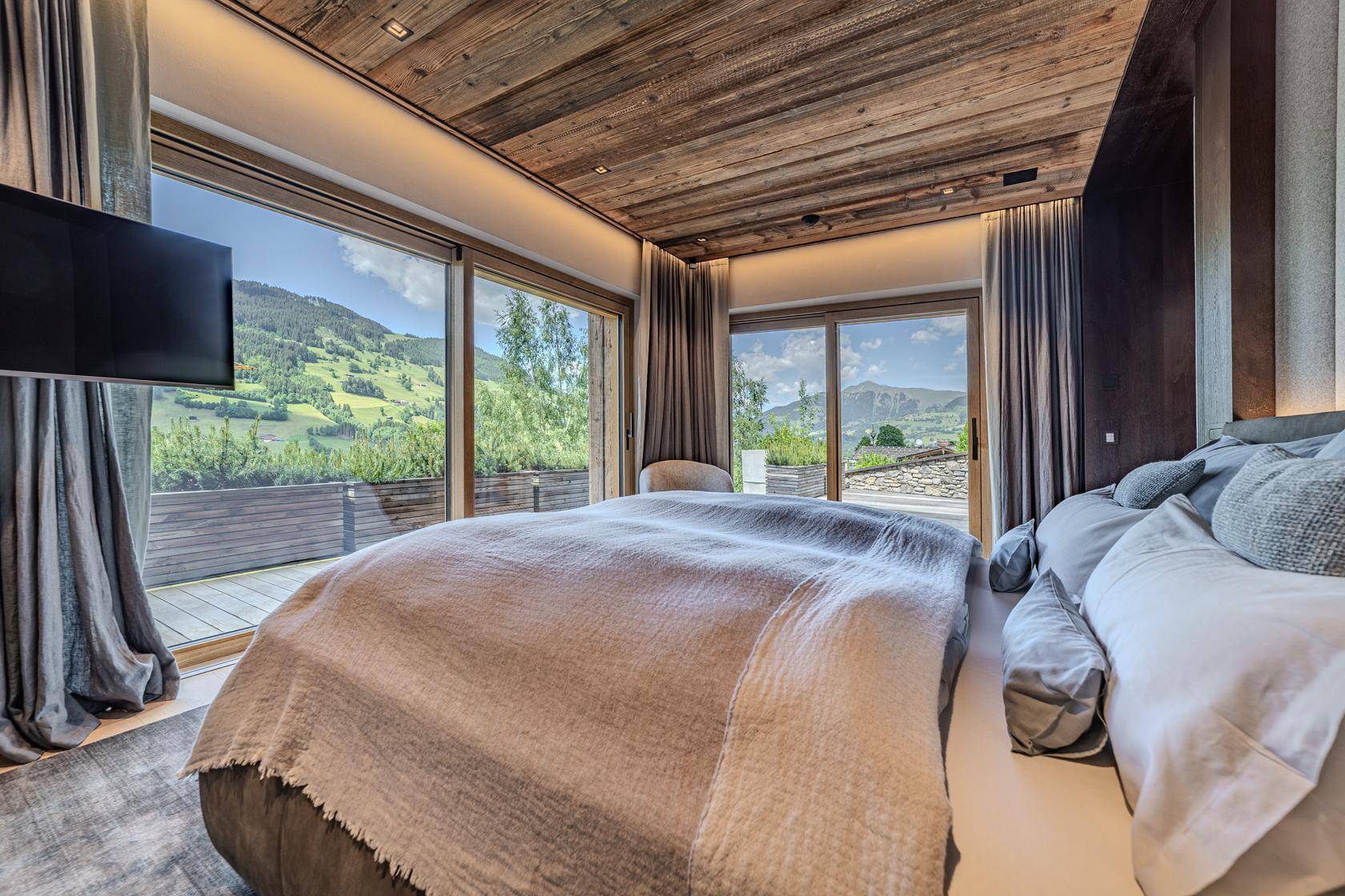 Komfortables Schlafzimmer mit großen Fenstern, Bergblick und direktem Zugang zur Terrasse.