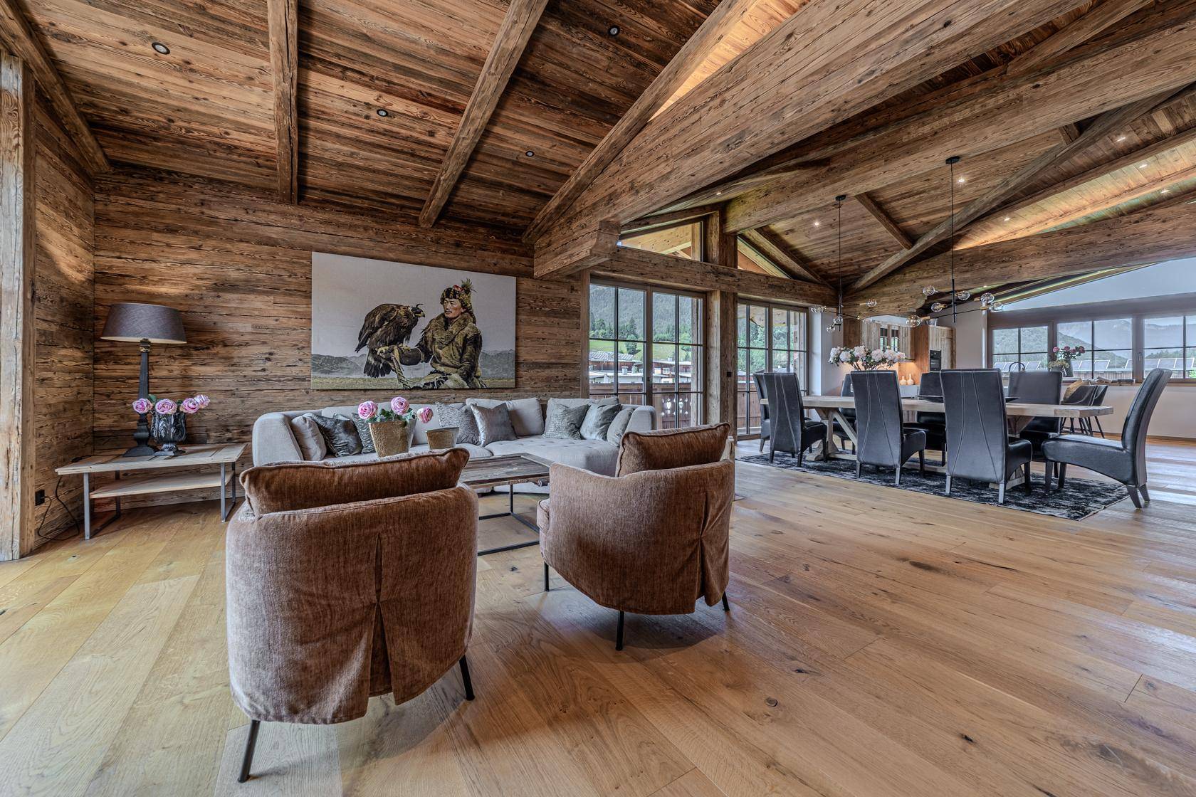 Gemütlicher Wohnbereich mit großem Sofa, Holzwänden und -decken, offen zum Essbereich und mit Bergblick.