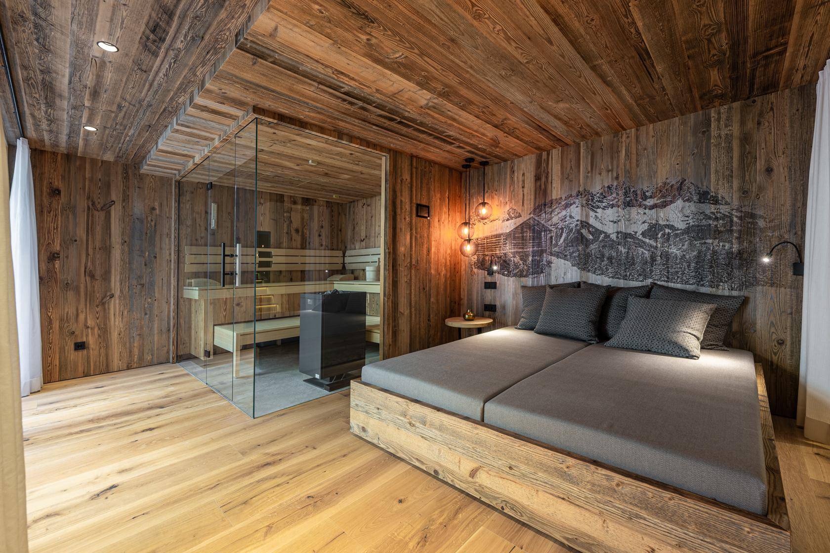 Schlafzimmer im Chalet-Stil mit Holzwänden, Holzboden und integrierter Glas-Sauna.