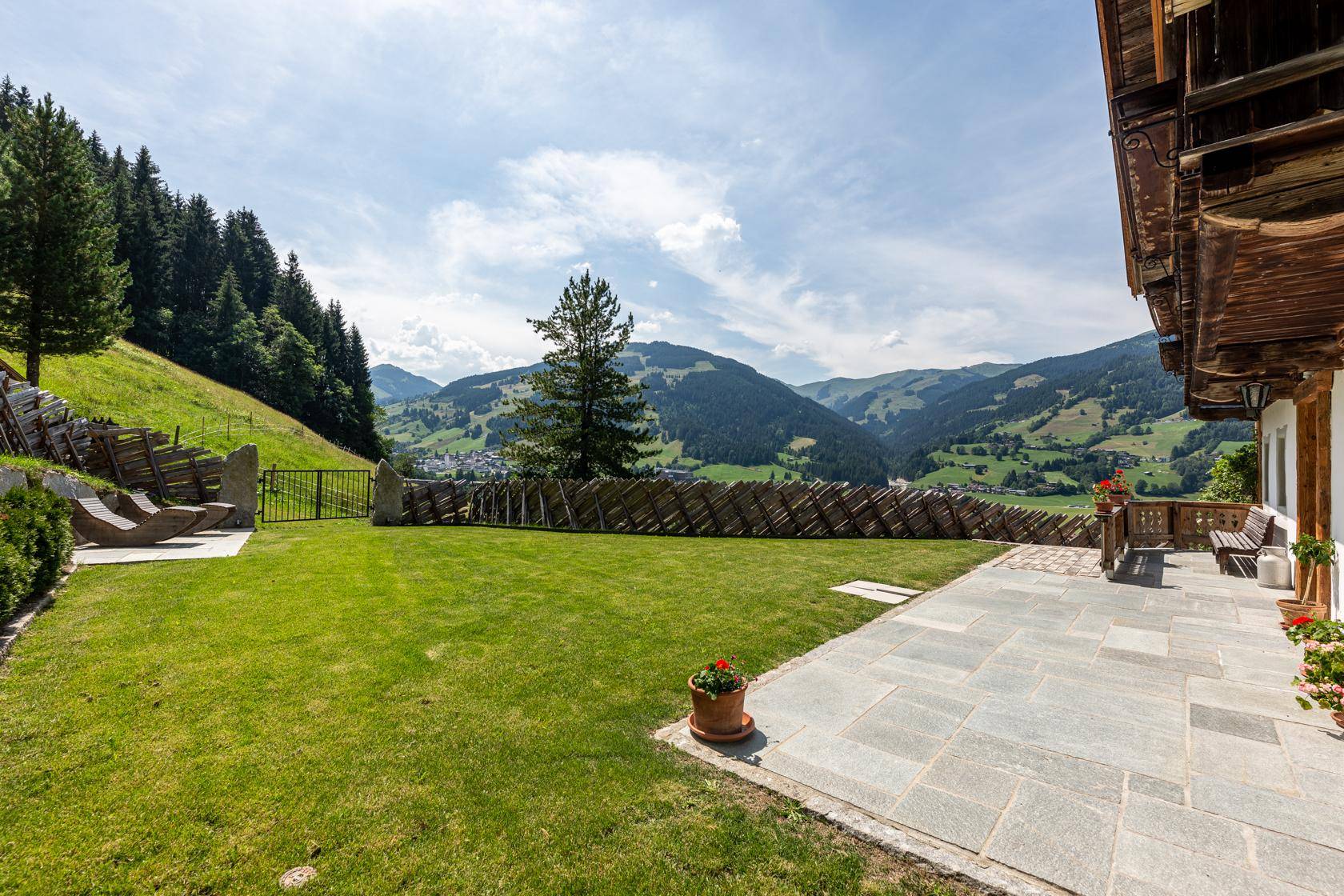 Gepflegter Garten mit Steinterrasse und weitem Blick über die Berglandschaft.