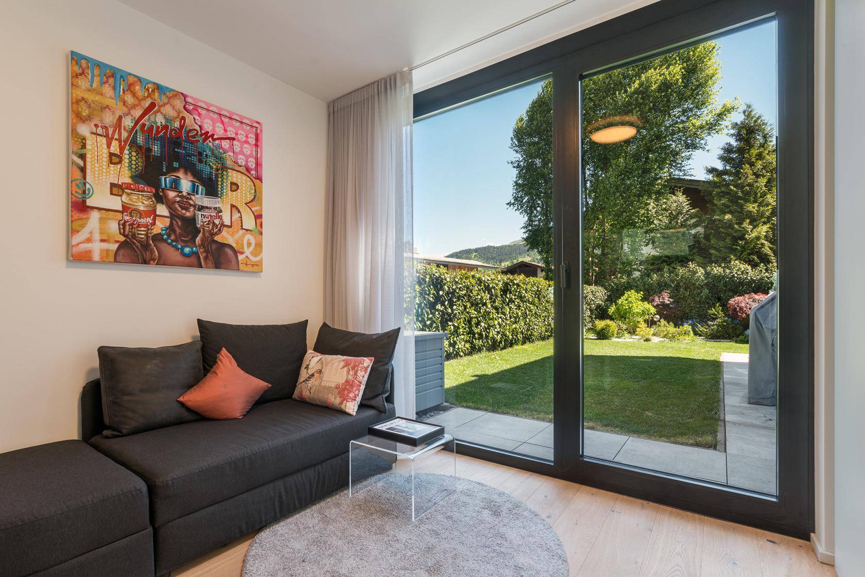 Gemütlicher Wohnbereich mit Sofa, moderner Kunst und Zugang zum Garten.