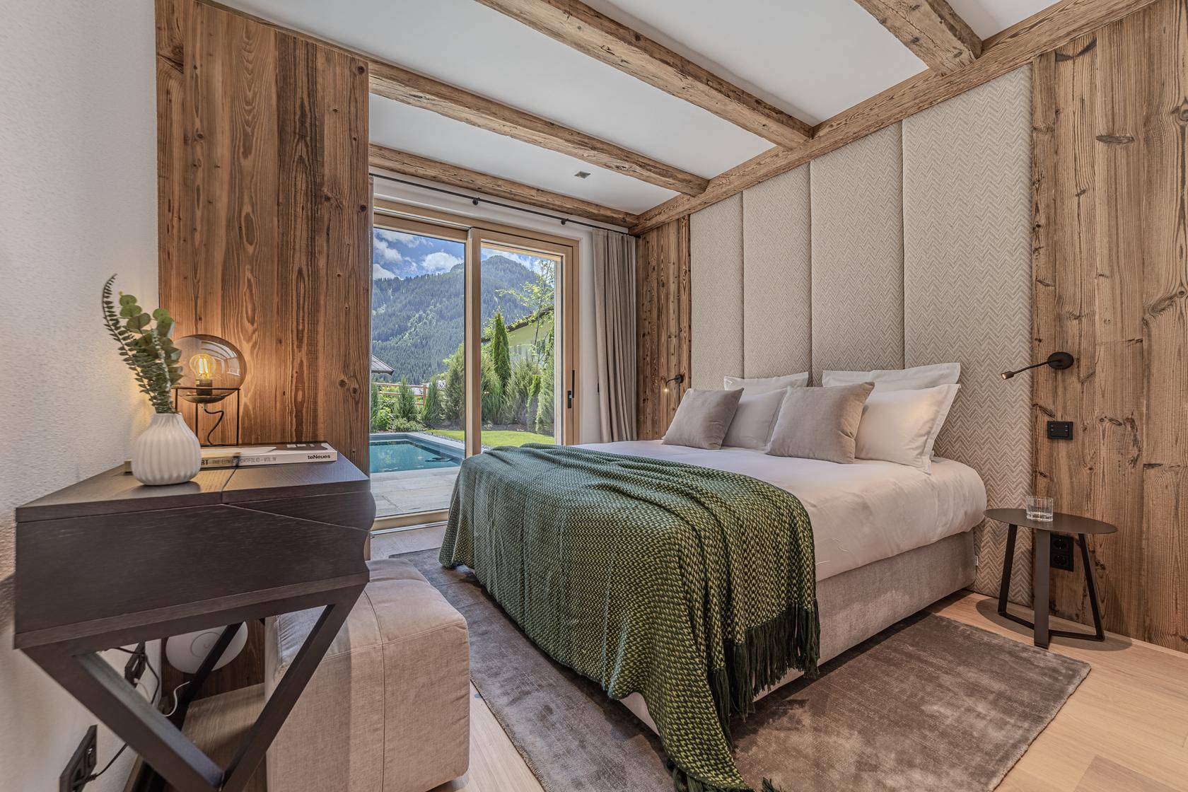 Helles Schlafzimmer mit direktem Zugang zum Pool und Blick auf die Berge durch die Terrassentür.