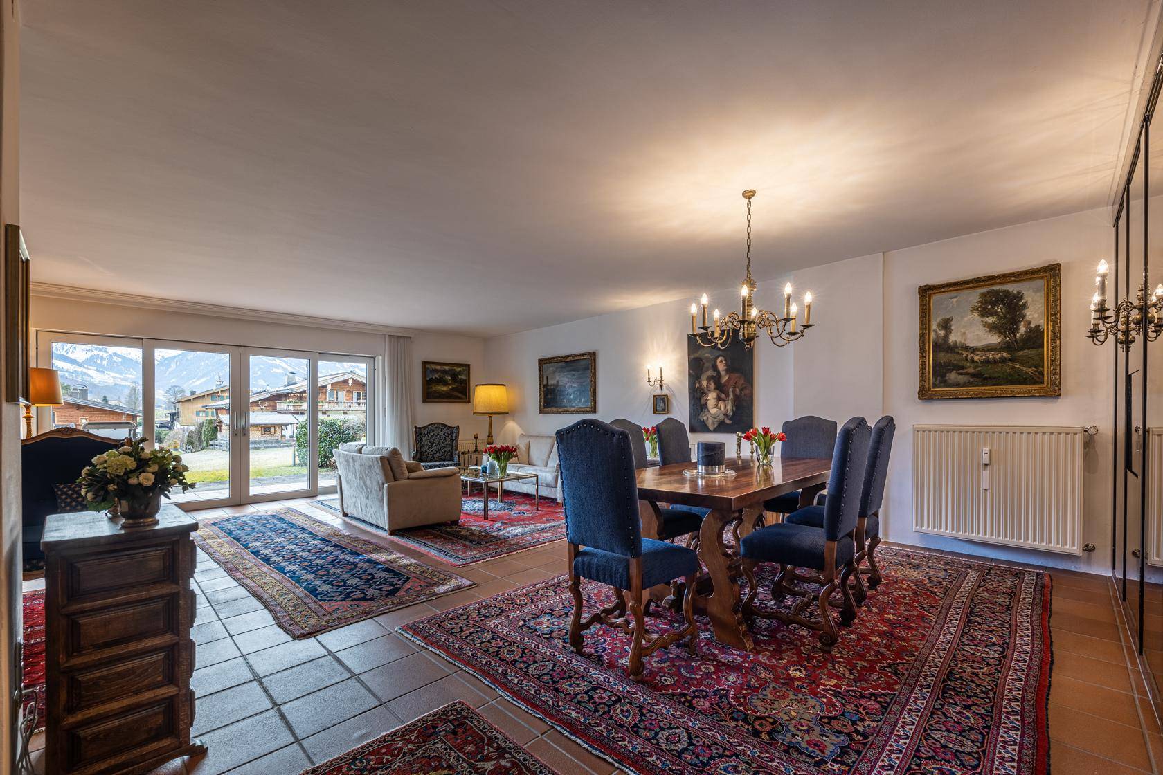 Klassischer Wohn-Essbereich mit eleganten Möbeln, persischen Teppichen und Zugang zur Terrasse.