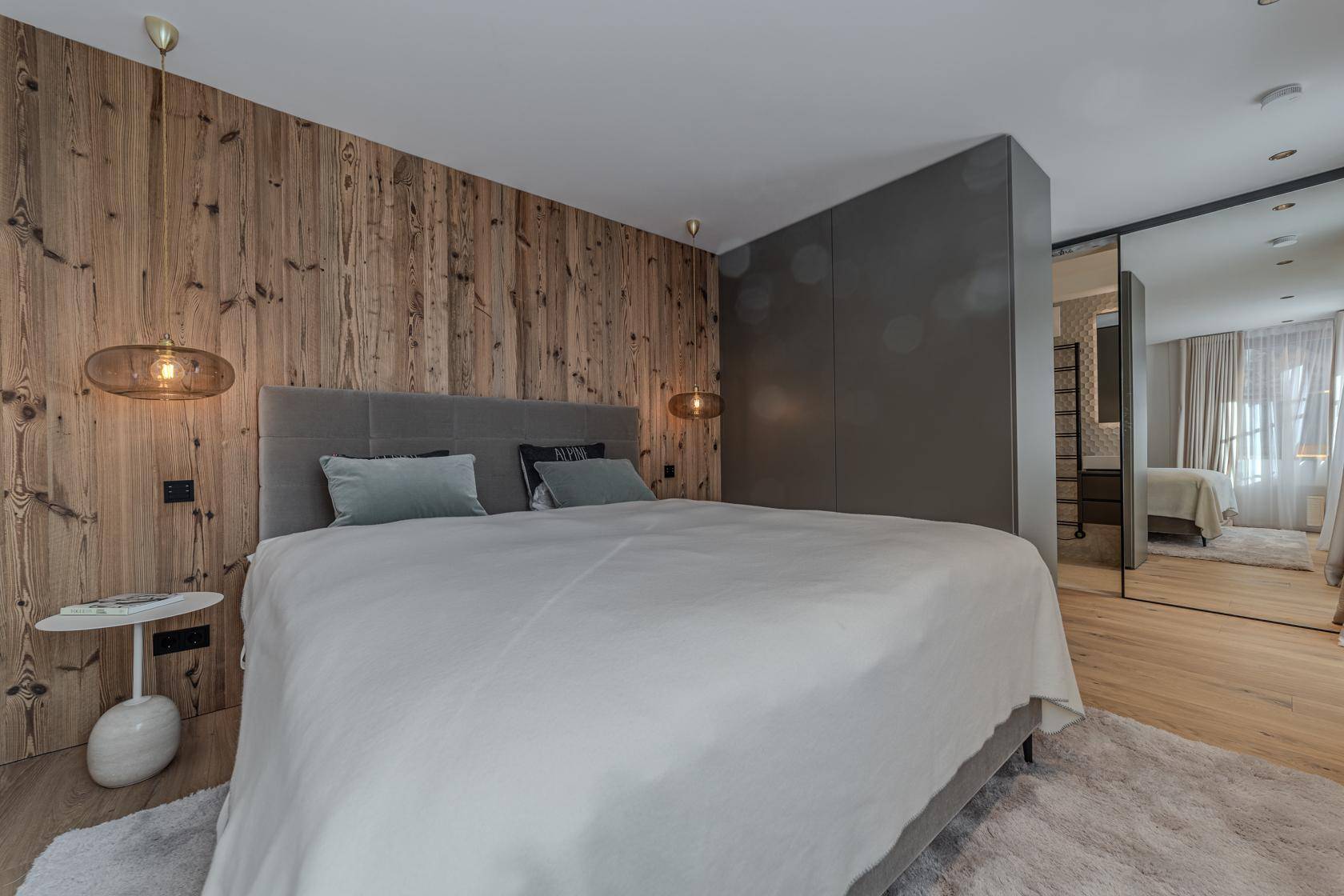 Stilvolles Schlafzimmer mit Holzwand, Doppelbett und integrierten Kleiderschränken.