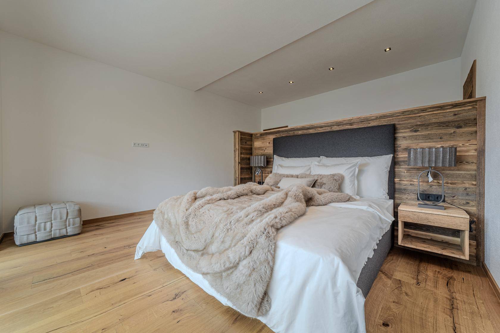 Geräumiges Schlafzimmer mit Holzboden, großem Bett und schlichter, eleganter Einrichtung.