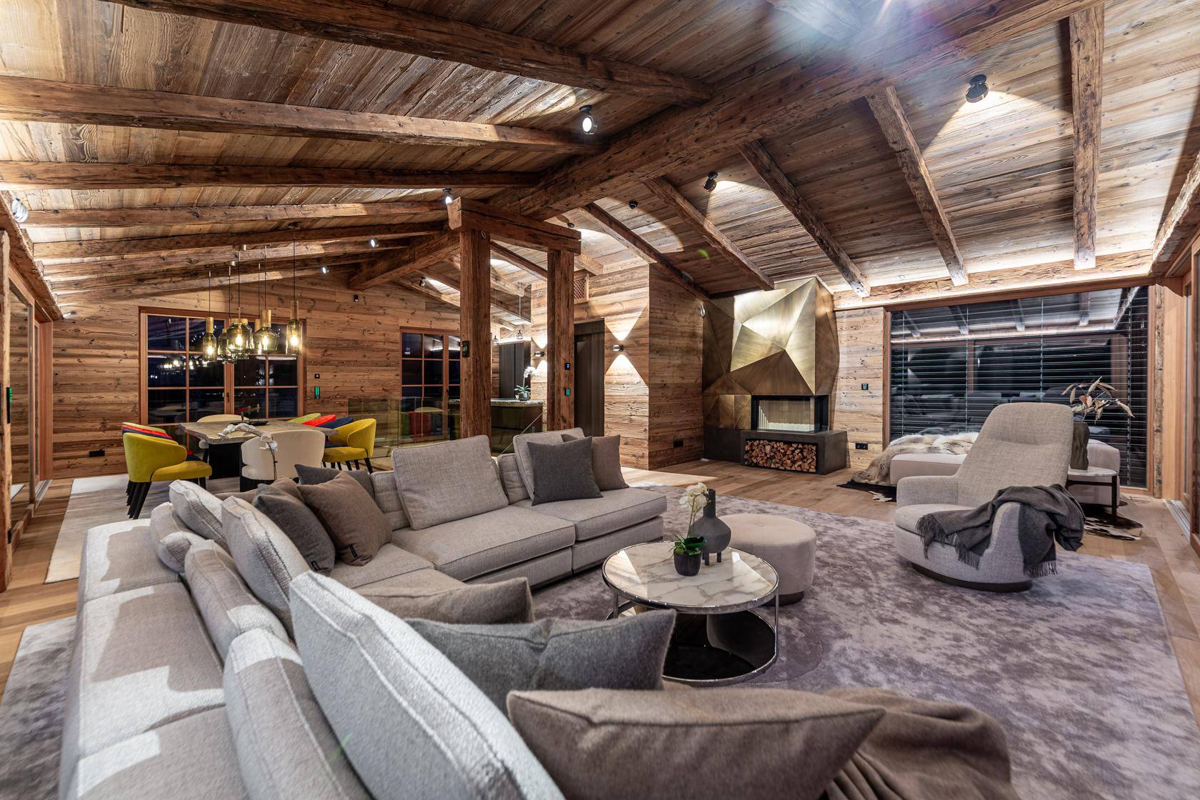 Geräumiges Wohnzimmer im Chalet-Stil mit Kamin, Holzbalken und Bergblick.