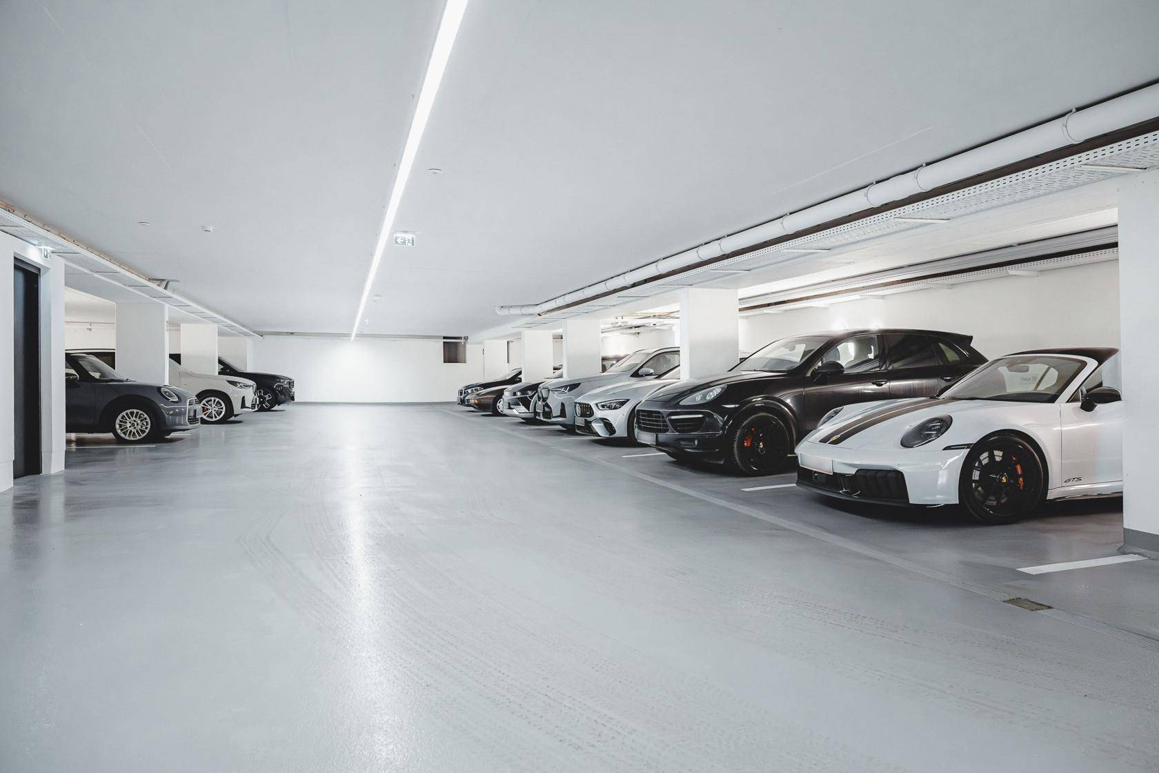 Geräumige Tiefgarage mit mehreren Stellplätzen und heller Beleuchtung für Fahrzeuge.