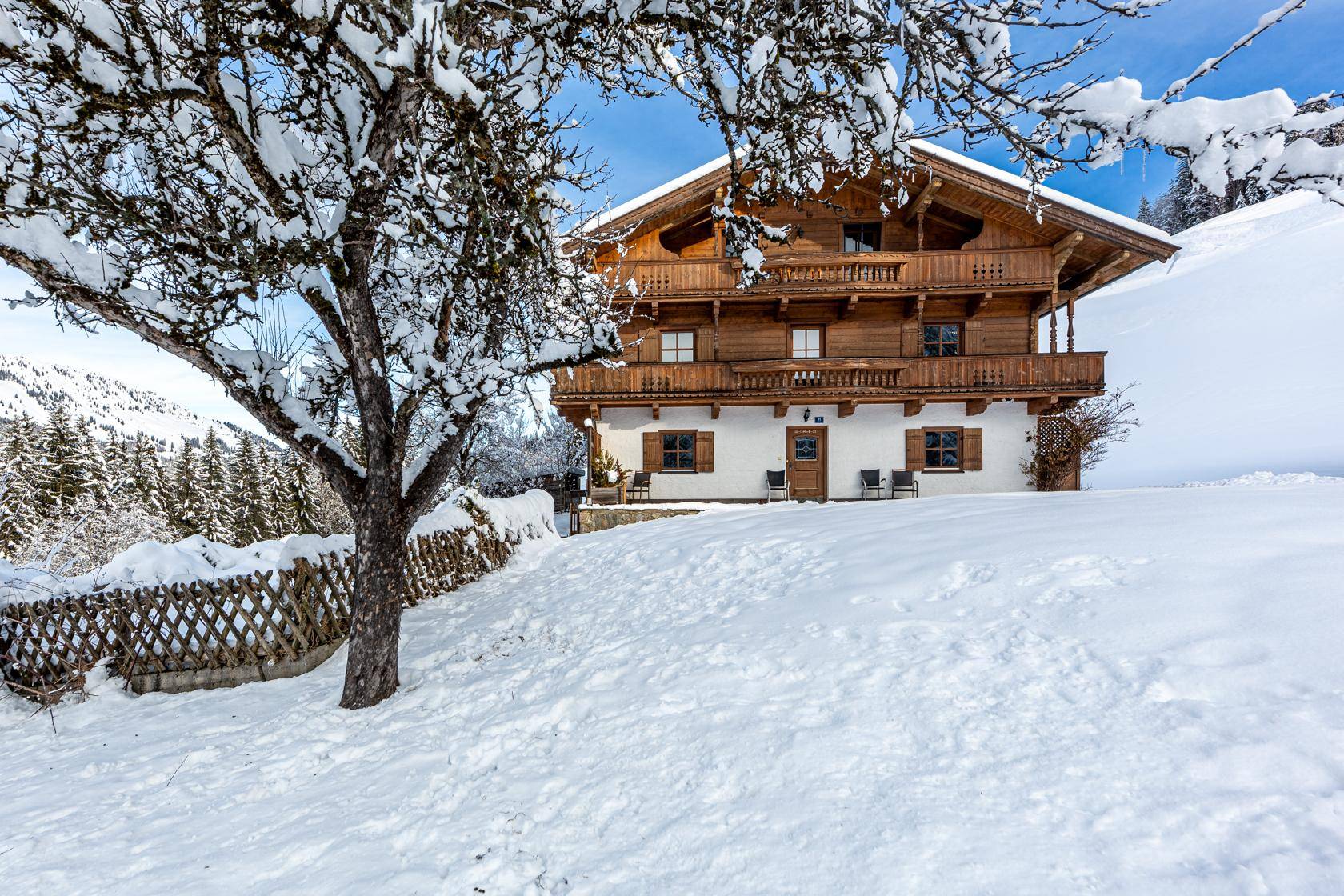 Charmantes Holzchalet in verschneiter Landschaft, mit Blick auf die umliegenden Berge und Wälder.